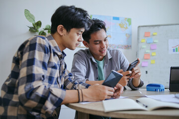 Obraz premium Two Young Men Intently Focused On Their Smartphone Sharing Moment