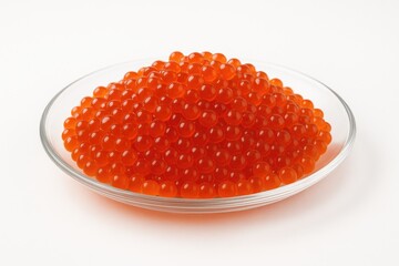 Close-up of bright red fish eggs on a clear dish against a white backdrop