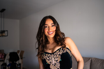 Arab woman with wavy hair smiles confidently while wearing a beautifully adorned traditional...