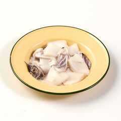 Fresh squid pieces in yellow enamel bowl, showcasing their clean and tender texture, perfect for cooking seafood dishes or grilling