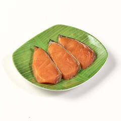 Fresh salmon fillets on green plate with leaf pattern, showcasing their vibrant orange color and...