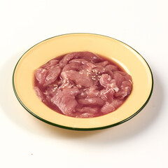 Fresh raw pork slices in yellow bowl, garnished with sesame seeds, ready for cooking or marinating, isolated on white background