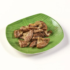 Grilled pork intestines served on green banana leaf plate, showcasing traditional Asian dish with crispy texture and savory flavor, perfect for food enthusiasts