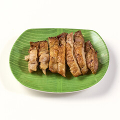 Grilled chicken slices served on green banana leaf patterned plate, showcasing golden brown, juicy texture, perfect for traditional or casual dining