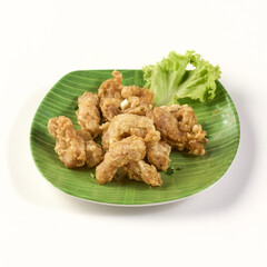 Crispy fried chicken tendons served on green banana leaf plate with fresh lettuce garnish, showcasing golden brown texture and appetizing appearance