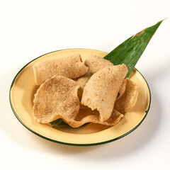 Crispy shrimp crackers served in yellow enamel plate with green leaf garnish, showcasing traditional snack with crunchy texture and savory flavor