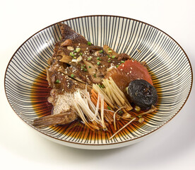 Beautifully plated dish of steamed fish head in soy sauce, garnished with mushrooms, green onions, and ginger, served in striped ceramic bowl. presentation is appetizing and elegant