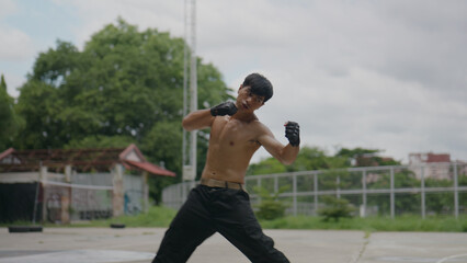 Asian man practicing boxing in a public park.