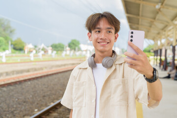 Young non binary tourist traveler in train station using phone