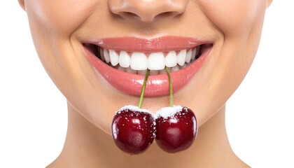 A close-up of a smiling mouth holding two fresh cherries with green stems between the teeth.
