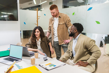 Business team working together, analyzing data on laptop and discussing project strategy in a bright, modern coworking space