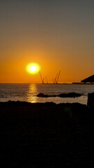 Sunset at Homem do Leme beach in Porto, Portugal, on July 8, 2025, showing silhouetted beach umbrellas and cranes against a golden sky, capturing a peaceful holiday evening by the Atlantic Ocean.