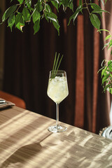 Elegant cocktail with ice and lemongrass in wine glass on wooden table