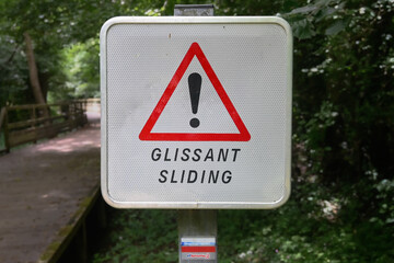 Warning sign with an exclamation mark and the text in French and English: Sliding. Naturally...