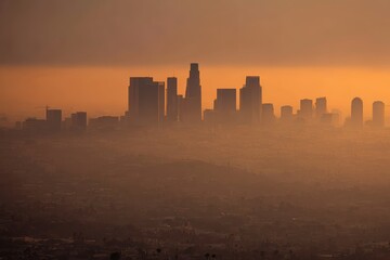 Fototapeta premium A hazy city skyline at sunset, with tall skyscrapers silhouetted against an orange sky and thick smog covering the urban landscape