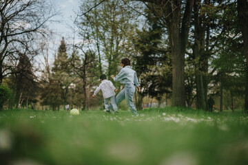 A mother and her child enjoy quality time playing in a lush green park, surrounded by trees and...