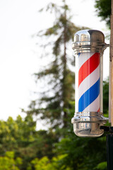 Classic Barber Pole Sign Outside Barbershop. Traditional red, white, and blue barber pole spinning...