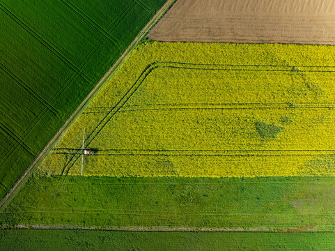 Aerial view of geometric fields of vibrant greens, yellows, and browns create a patchwork quilt across the landscape in Wittenheim, Grand Est, France.