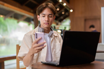Handsome young non binary man sitting in cafe restaurant using laptop computer