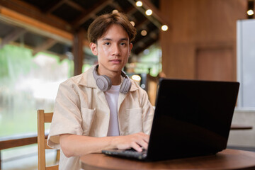 Handsome young non binary man sitting in cafe restaurant using laptop computer