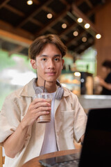 Handsome young non binary man sitting in cafe restaurant using laptop computer
