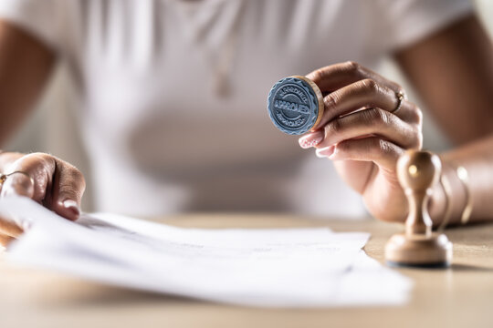 A notary, judge or other official holds a stamp that says Approved. Concept of official permission at the office, post office, at the notary at the court or other institution.