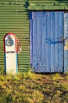 An old petrol bowser in front of a farm shed