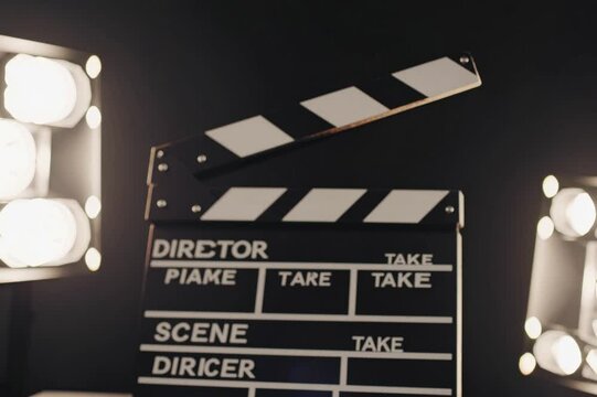 Clapperboard and script ready for filming in an illuminated studio setting with stage lights and creative vibe