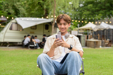Young non binary person having road trip and camping with friends in nature using phone