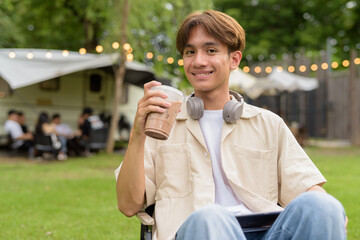 Young non binary person having road trip and camping with friends drinking chocolate drink