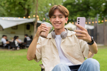 Young non binary person having road trip and camping with friends in nature taking selfie photo...