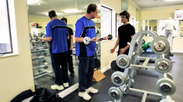 Fitness trainer helping middle aged man work out 