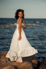 Ocean Breeze Elegance: Woman in White Dress on Coastal Rocks
A woman in a flowing white dress...