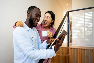 Overjoyed multiethnic couple using laptop, shopping online with sales, playing game together
