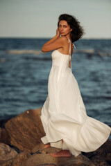Ocean Breeze Elegance: Woman in White Dress on Coastal Rocks
A woman in a flowing white dress...