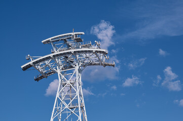 Cableway tower against the background of the sky with clouds. The support made of metal structures under construction. View from below.