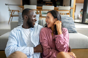 Young diverse multiethnic couple moving in new home. Couple is having fun in new house at moving day