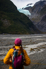 girl in yellow jacket standing at Franz Josef Glacier Viewpoint, admiring the blue glacier tongue...