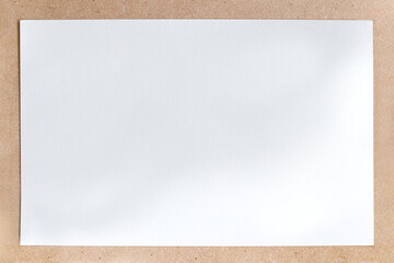 Top view of white empty canvas drawing paper on brown wooden board as frame border for graphic design space and information message sign board.