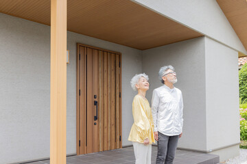 笑顔で住宅の前に立つシニアカップル