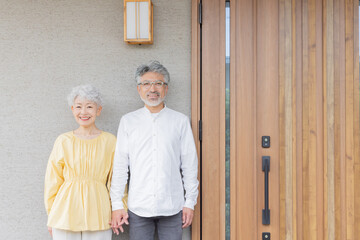 笑顔で住宅の前に立つシニアカップル