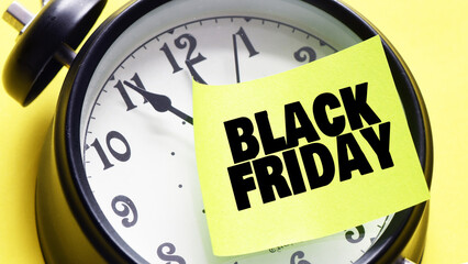 BLACK FRIDAY words on a small piece of paper taped to an alarm clock. November is promotion time in stores and online.