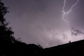 Dramatic Lightning Bolt Illuminating a Dark Sky Over a Rooftop