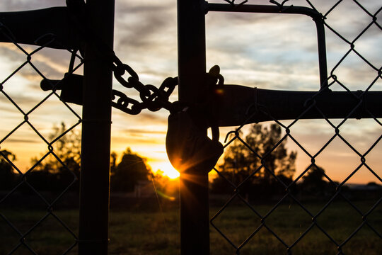 Morning sun shining through silhouetted padlock and gates