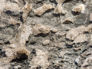 Close-up of rough stone surface with irregular texture, natural erosion patterns and earthy colors,...