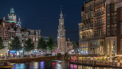 Panoramic night timelapse of Amsterdam city center featuring Amstel River, waterfront and Munttoren tower. Netherlands