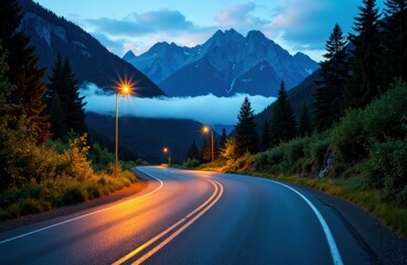 Naklejka premium Serene mountain road at dusk with streetlights illuminating the winding path and towering peaks in the background