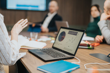 Business colleagues engage in project analysis using charts and reports at a meeting, highlighting...