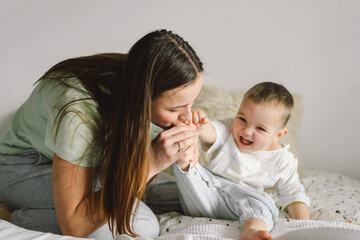 Home portrait of a baby boy with mother on the bed relaxing and playing in the bed at the weekend...