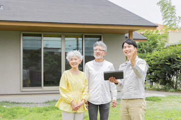 住宅の前で説明する男性作業員とシニア夫婦